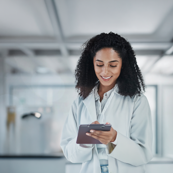Woman with curls in a white coat looks at tablet