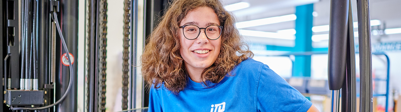 A woman in an iTD blue shirt sitting on a forklift