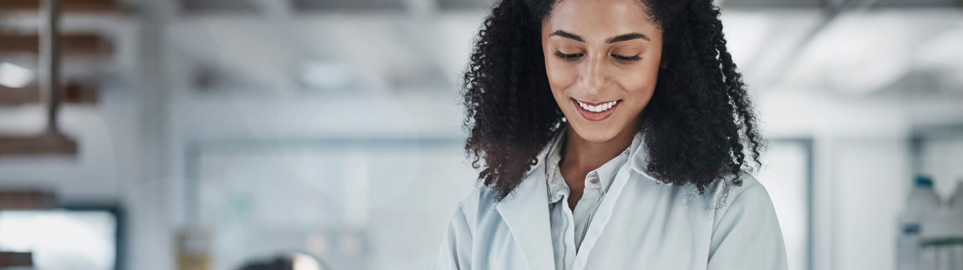 Woman with curls in a white coat looks at tablet