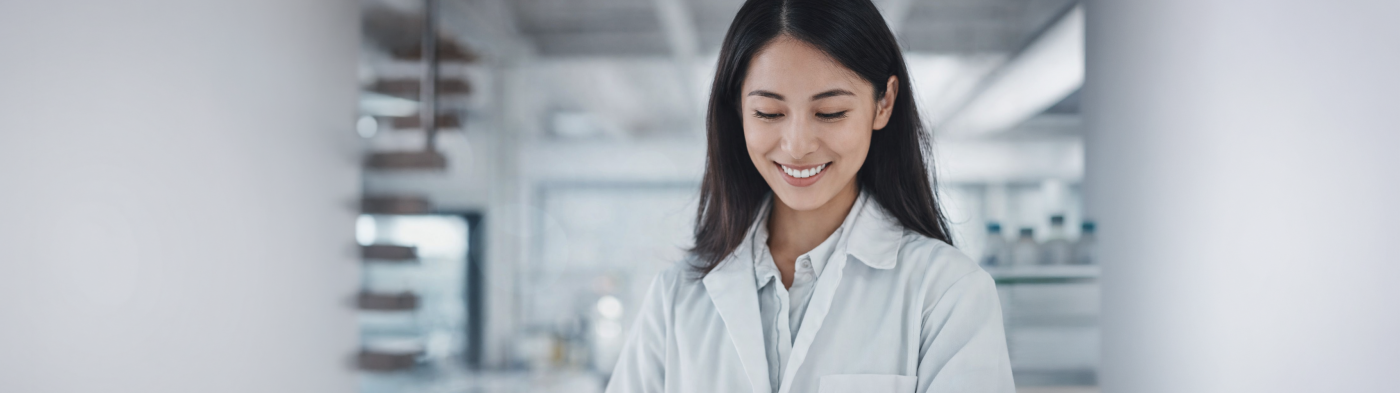 Asian women in a white coat looks at tablet