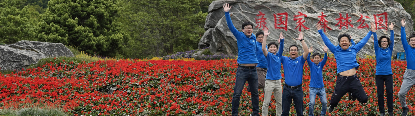 Group of people in blue iTD shirts jumping in front of large rock
